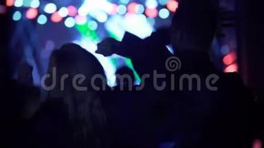 快乐的女人和男人在音乐节上挥舞双手跳舞，夜生活